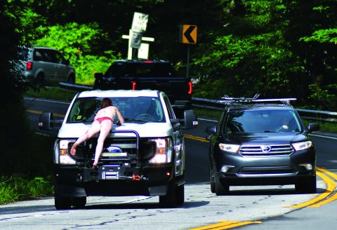 Enoch Autry/The Clayton Tribune. A female wearing only underwear lays on the hood of a Georgia Power pickup as the truck attempts to slow down on Highway 76 West for the safety of the woman. Sherry Sue Turpin was charged on June 29 by Rabun County Sheriff’s Office deputies with pedestrian under the influence of alcohol or drugs after witnesses say Turpin climbed off the hood to the truck. The incident caused stopped traffic in both directions.