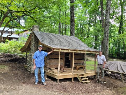 Megan Broome/The Clayton Tribune. Barry Stiles, Foxfire museum director (left) and Todd Faircloth, Foxfire executive director, showcase the miniature replica of the Warwoman Cabin as part of the new Children’s Village.