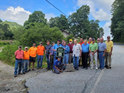 Megan Broome/The Clayton Tribune. A crowd of surveyors and community members from Georgia, North Carolina and surrounding areas gather on Hale Ridge Road at Commissioners Creek at the state line on Aug. 13 to replace and document a surveying monument, dating back to 1819, on Commissioners Rock. 