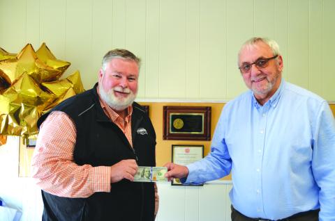 Linda Erbele/The White County News. Richard Clark (left) accepts $100 from Wayne Knuckles, The White County News publisher, for his photograph of colorful leaves. Clark’s photo was chosen for the cover of the fall 2022 edition of The Mountain Traveler which can be found in Rabun and neighboring counties.