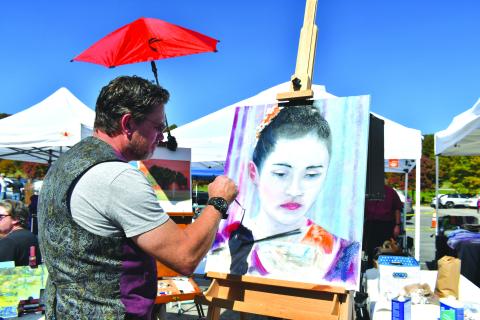 Megan Broome/The Clayton Tribune. Megan Broome/The Clayton Tribune. Alan Corbett showcases his talent and paints a portrait while visitors check out the various crafts and artwork set up during the Sky Valley Fall Fest last weekend. 