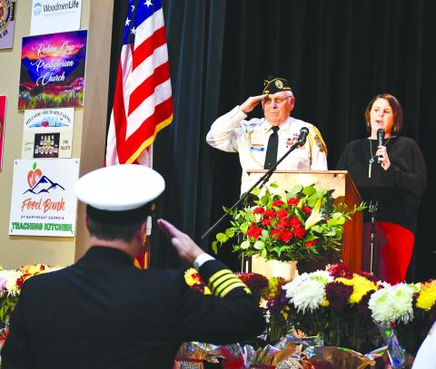 Megan Broome/The Clayton Tribune. Veteran Doug Wayne and fellow soldiers salute the American Flag as Lora Burrell sings The Star-Spangled Banner at the opening of the Veterans Appreciation Dinner held at the Rabun County Civic Center. 