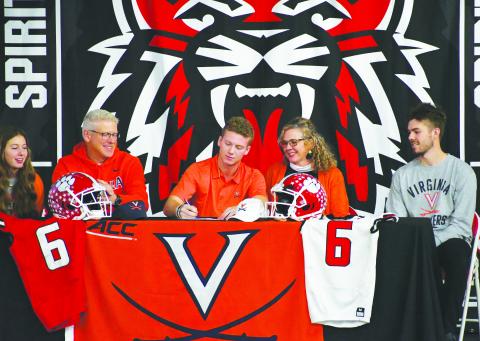 Luke Morey/The Clayton Tribune. Surrounded by his family, senior wide receiver Jaden Gibson (center) signs his letter of intent with Virginia on Wednesday, Dec. 21. The other Gibsons on the stage include from left, Janakate, Jason, Jennifer and Jasper.