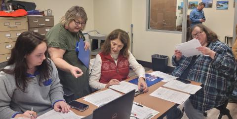 Megan Broome/The Clayton Tribune. Shay Harbin, office assistant; and poll workers Lynne Ramey; Kathy Allen, and Amanda Burrell work at the Rabun County Board of Elections Office after polls closed for the Dec. 6 U.S. Senate runoff, which saw over 50 percent of voters in Rabun County cast their ballots. Shown in the background is Zarek Echols, technician. 