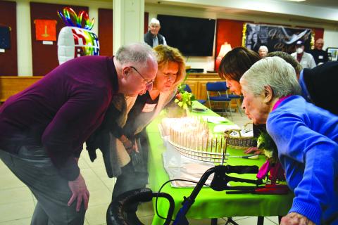 Megan Broome/The Clayton Tribune. Allie Moseley, right, blows out 100 candles on her birthday cake with help from friends and family members Bo Cribbs, Debby Moseley, and Cindy Wallis. Friends and family members gathered for Moseley’s centennial birthday party on Dec. 5. 