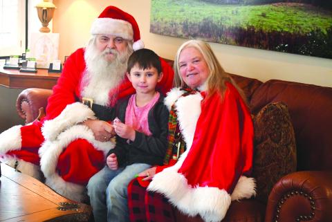 Megan Broome/The Clayton Tribune. Santa and Mrs. Claus took a break from Christmas preparations at the North Pole to visit with children in Rabun County Monday. The cheerful duo was spotted at Better Homes and Gardens Real Estate Metro Brokers in Clayton. The business was decorated with Christmas cheer and Santa and Mrs. Claus passed out cookies and candy canes to children. Pictured is 6-year-old Jace Shirley who is excited to meet Santa and Mrs. Claus. 