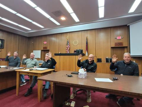 Megan Broome/The Clayton Tribune. Rabun County Commissioners Will Nichols, Kent Woerner, Chairman Greg James, Scott Crane and Tom Garrison raise their hands as they unanimously approve the first reading to amend the zoning ordinance for short-term rentals at Tuesday’s commission meeting.