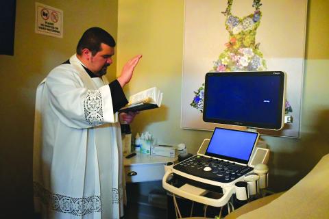 Megan Broome/The Clayton Tribune. Father Luis Alvarez blesses the new ultrasound machine. 