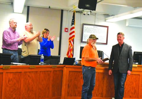 Megan Broome/The Clayton Tribune. Clayton Mayor Kurt Cannon, right, presents Streets Department worker Everiest Turpin with a plaque thanking him for his years of service to the city after he announced his retirement. Turpin received a standing ovation from council members and attendees, and pictured are council members Woody Blalock and David Cross and City Manager Trudy Crunkleton congratulate Turpin during his 18th year of service. 