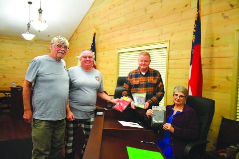 Megan Broome/The Clayton Tribune. Johnnie Robinson, president of the Board of Directors of Creating Ties that Bind, and Pam Wheeler, CEO of Creating Ties That Bind (left) present a United States flag, State of Georgia flag, and POW flag to Tiger Mayor Mike Carnes, center, and the Tiger Town Council at the Feb. 13 council meeting. Also pictured is Tiger Town Council member Karen Lovell. 