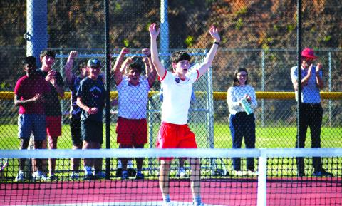 Luke Morey/The Clayton Tribune. With his teammates and classmates cheering in the background, RCHS freshman singles tennis player Brady Darnell raises his arms in victory for his three-set Tuesday win that propelled the Wildcats into the Sweet Sixteen.