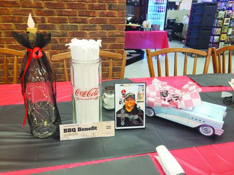 Megan Broome/The Clayton Tribune. Tables were decorated with pictures honoring Justin Bowen’s life, candles, model classic cars with trunks filled with tootsie roll candies and lighted display bottles at the BBQ benefit. 