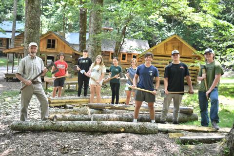 Megan Broome/The Clayton Tribune. Local students participate in the Foxfire Summer Leadership Program and help Foxfire Museum Director Barry Stiles hew logs to prepare building the miniature replica Blacksmith Shop that will be featured at The Children’s Village. Pictured are Stiles; Rabun County High School students Luke Thompson, Sam Flaherty, Celton Littrell, Sean Flaherty, Brinn Justice, and Gavin Sharpe; Rabun Gap-Nacoochee School student Lily Karplus; and home-schooled student Olivia Nixon. 
