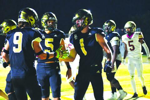 Luke Morey/The Clayton Tribune. Junior Trey Horne (1) celebrates with teammates Marshall Pritchett (9) and Gavin Owens after Horne’s fourth touchdown of the night in the playoffs in November 2022.