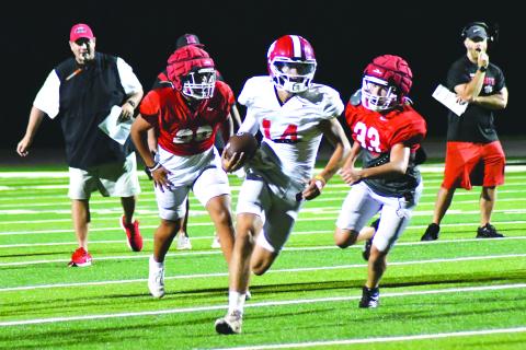 Enoch Autry/The Clayton Tribune. Sophomore starting quarterback Ty Truelove slips through the Wildcat defense for a gainer on the ground as RCHS head coach Michael Davis (left) watches in the background.