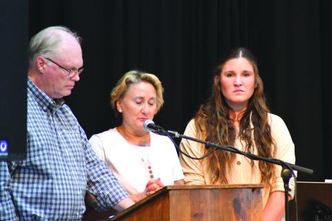Enoch Autry/The Clayton Tribune. Breck Patterson, Lisa Patterson and their daughter Cylvie stand before the audience at the Rabun County Civic Center to talk about the life of Chan Patterson, a firefighter who died in a boating accident in June 2021 on Lake Tugalo in Rabun County. Search and Rescue consoled the Patterson family. Below:  Sheriff Chad Nichols sits with his 6-year-old son Chatham at the banquet.