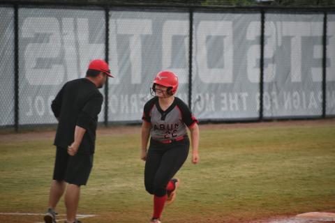 Wade Cheek/The Clayton Tribune. Lady Cat catcher Chloe Erlewine smiles as she rounds third base past RCHS head coach Wesley Satterfield after she homers on Oct. 19.