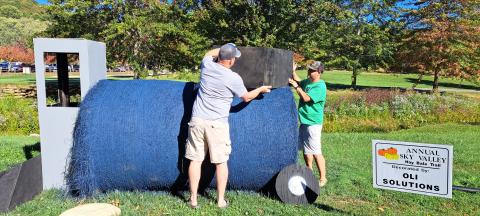 Megan Horn/The Clayton Tribune. Chip Oliver and Brandon Culpepper work on decorating a tractor for OLI Solutions as part of the Sky Valley Hay Bale Trail. Left: Noryce and Don Burgey decorate a bale in the Sky Valley Hay Bale Trail for Bartram Trail Conservancy to bring awareness to and promote the 110-mile trail. 