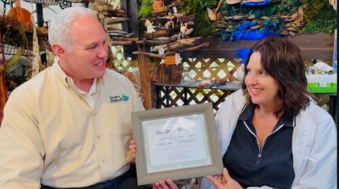Photo courtesy Forward Rabun/Rabun County Chamber of Commerce. Rick Story, president of Forward Rabun/Rabun County Chamber of Commerce, presents Melissa Heiden with a Certificate of Appreciation for hosting one of the year’s best Open House Events. Left: Those in attendance at the open house event bought some of the beautiful garden items at the Lakemont garden business.
