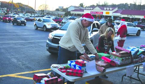 Enoch Autry/The Clayton Tribune.  Food Bank of Northeast Georgia Branch Manager James Brim and Victoria Anderson help with the presents that are given out to the children at the outdoor event in the Covered Bridge Shopping Center. 