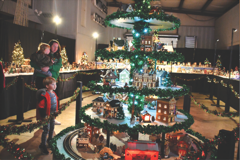 Megan Horn/The Clayton Tribune. The Stille family of Spencer, 1, Jennifer, and Sutton, 4, gaze at the miniature village that includes a train. Left: Five-year-old Ethan Moseley hugs The Grinch at the Village of Lights.