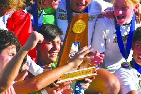 Wade Cheek/The Clayton Tribune. Rabun Gap goalkeeper Agustin Canales smiles as he looks down at the 2023 NCISAA championship trophy after RGNS won the NCISAA state title. The championship was the Eagles’ third straight.