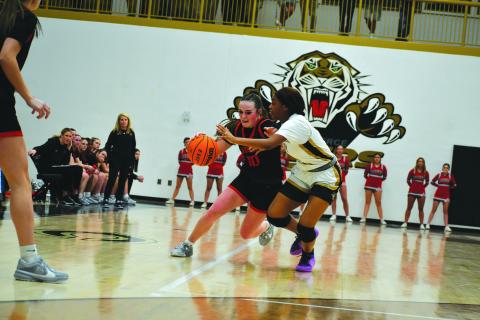 Wade Cheek/The Clayton Tribune. With Lady Cat head coach DeeDee Dillard, the RCHS players, and RCHS cheerleaders watching, senior Mili Watts makes her move to the basket against the Lady Tigers in Commerce.