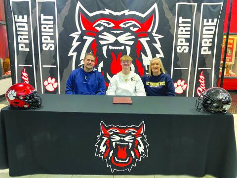 Submitted. RCHS senior football player Hayden Ross (middle) signs to play collegiately at East Tennessee State University with his parents by his side on Feb. 7. Ross will be a specialist/long-snapper for the Buccaneers. 