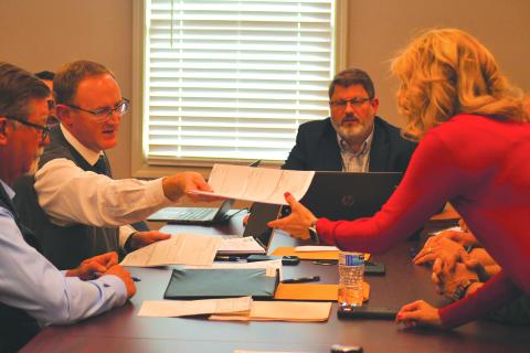 Enoch Autry/The Clayton Tribune. City of Clayton Attorney Mitch Baker hands RCWSA Finance Manager Traci Adams checks to help complete the sale of the water and sewer system on Monday at the new Clayton office.