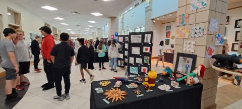 Megan Horn/The Clayton Tribune. Students at Rabun County Schools enjoy colorful artwork created using various mediums by fellow students during the RCMS and RCHS Art Showcase held in the Fine Arts Building May 16. Left: RCHS senior Ryleigh Brotherton displays artwork in red clay titled “Friendly Miner” during the Rabun County High School and Rabun County Middle School Art Showcase held in the Fine Arts Building (FAB) May 16. 