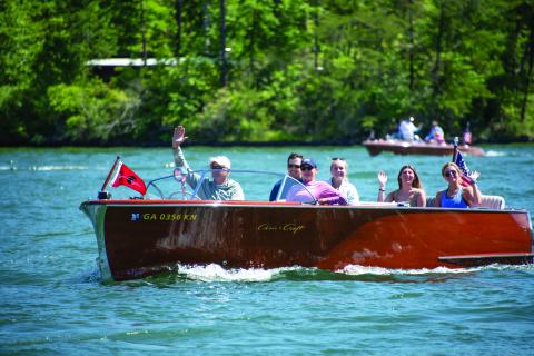 Submitted photos. Wooden boat during the parade on Lake Burton. Boat owner waves to the crowd.