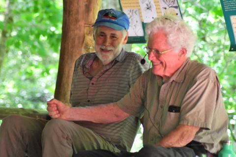 Enoch Autry/The Clayton Tribune. John Lane and Doug Woodward share a laugh at the picnic area at Warwoman Dell. Lane, an author, and Woodward, a former stuntman, told people at the event about the early days of the designation for the river. Left: Volunteer Jim Chance chops trees in the Warwoman Dell area as part of the early morning cleanup. Others walked trails picking up trash.