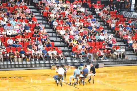 Wade Cheek/The Clayton Tribune. Star football players Charlie Woerner, Gunner Stockton and Malaki Starks sit with Clayton Baptist Church Senior Pastor Joey Thompson on Ken Byrd Court in front of hundreds in the Rabun County High School gymnasium during last Sunday’s Night of Champions on July 14. 