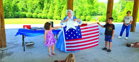 Megan Horn/The Clayton Tribune. Mary Lou Goehring from the Georgia Cameo Society dresses in 1800s fashion and presents a summer reading program describing the events that inspired Francis Scott Key to write the poem that eventually became the National Anthem of the United States of America. Children participate in the demonstration. 