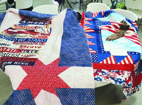 Submitted photo. Patriotic quilts created by the Northeast Georgia Chapter of Quilts of Valor will be presented to Active Duty and Veteran members of the military. Below: Jeanie Whitworth makes a red, white and blue quilt during the “Quilt-a-thon” April 18-20 with the Northeast Georgia Chapter of Quilts of Valor.