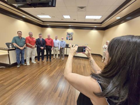 Enoch Autry/The Clayton Tribune. Anglea Cole takes a photograph of the Rabun County school board members and her husband Steven Cole (center) after Steven Cole was officially approved as the school system’s new superintendent. Standing on the far right is retiring superintendent Dr. April Childers. 