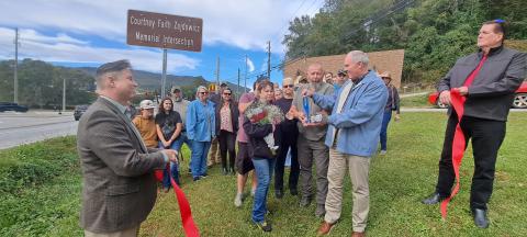 Megan Horn/The Clayton Tribune. Forward Rabun/Rabun County Chamber of Commerce members, family and friends, as well as local officials and community members cut the ribbon on the Highway 76 and Highway 441 “Courtney Faith Zajdowicz Memorial Intersection.” Zajdowicz passed away on Sept. 1, 2021.