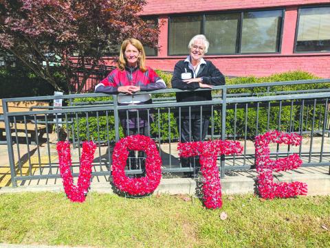 Photo courtesy of Tammy Whitmire. Rabun County Elections Office Poll Workers Kathy Allen, left, and Ann D’Agostino pose in front of this handmade sign encouraging the community to VOTE. D’Agostino made the artwork from the seals taken off of the Ballot Marking Device (BMD) every day. 