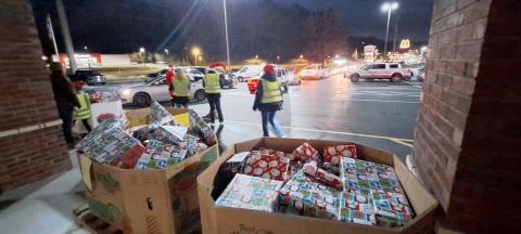 Megan Horn/The Clayton Tribune. Volunteers at the Food Bank Toy Drive prepare to hand out gifts as a row of vehicles wraps around the Food Bank parking area on Monday. 