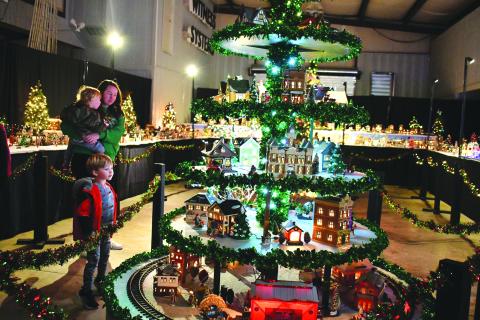 File photo/Megan Horn. The Stille family of Spencer, Jennifer and Sutton gaze at the miniature village that includes a train at last year's Village of Lights benefitting Fight Abuse In The Home (F.A.I.T.H.). 