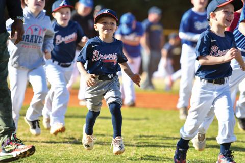 Wade Cheek/The Clayton Tribune. Davis Leverette joins the rest of RCLL in running to home plate for a performance by former MLB player and musical artist CJ Beatty. RCLL held its opening day ceremony to kick off the new season. 