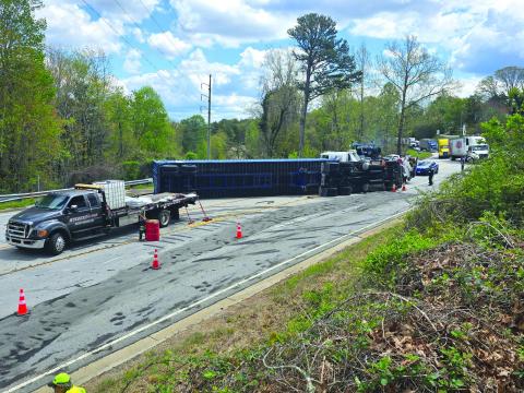 Enoch Autry/The Clayton Tribune. : A tractor trailer rests on its side on Highway 441 in Tallulah Falls on April 11 as crews attempt to clear the scene and get the vehicle upright. 