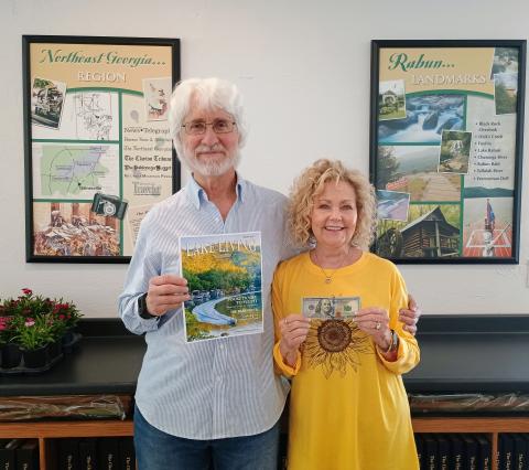 Megan Horn/The Clayton Tribune. Spring 2025 “Lake Living” cover winner Morgan Harvill (left) is pictured with his wife, Judy. The magazine cover features a MasterCraft boat on Lake Rabun in Rabun County at the narrows around September 2024. In addition to gracing the cover of Spring 2025 “Lake Living,” Harvill received $100. 
