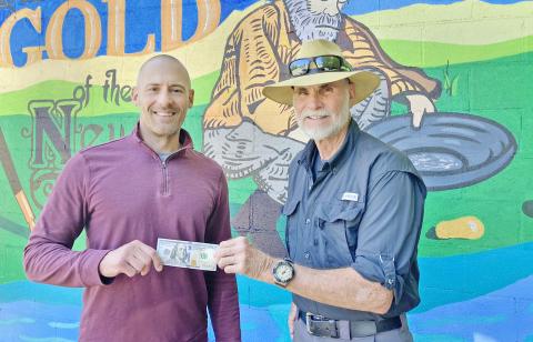 Photo/Keith Murden, CNI News Service. The Dahlonega Nugget Publisher John Bynum (left) presents the $100 prize to Dahlonega resident Bill Perdue for his winning cover photo of a beautiful summer sky above Lake Winfield Scott.