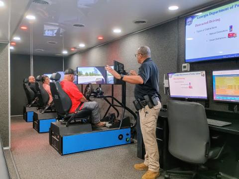 Megan Horn/The Clayton Tribune. Officer Hammock with the Georgia Department of Public Safety Motor Carrier Compliance Division instructs Transportation Department employees on driver education safety with a driving simulator. Rabun County Schools held its back to school meeting on July 29 at the Rabun County Board of Education. 