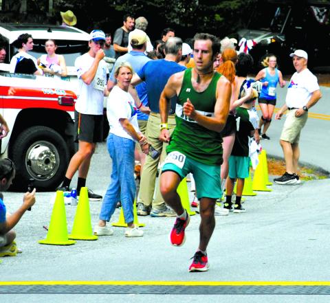 Enoch Autry/The Clayton Tribune. Ben Perrin crosses the finish line as the first overall male in the Rabun Ramble 10K.