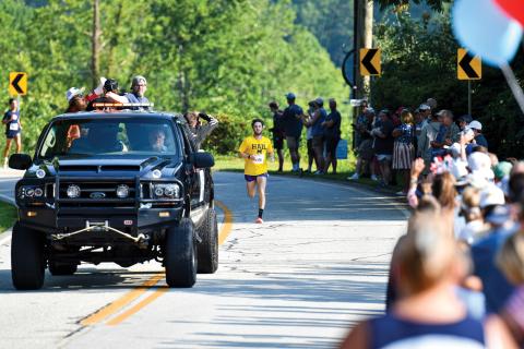 Wade Cheek/The Clayton Tribune. Led by the pace car, Nolan Weisdorfer sprints toward the finish line to repeat as the overall winner of the Lake Burton Fun Run on Saturday, July 5. 