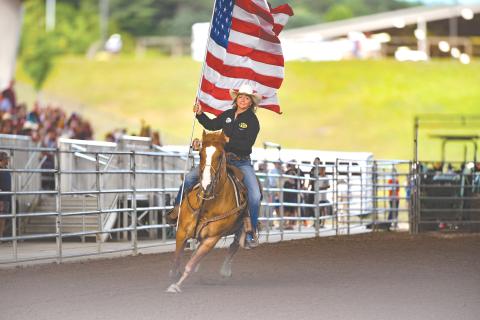 Wade Cheek/The Clayton Tribune. Jamie Ellsworth rides through Rabun Arena with the Stars and Stripes during the opening ceremonies of the Rabun Arena Rodeo 2024 Fourth of July weekend. 