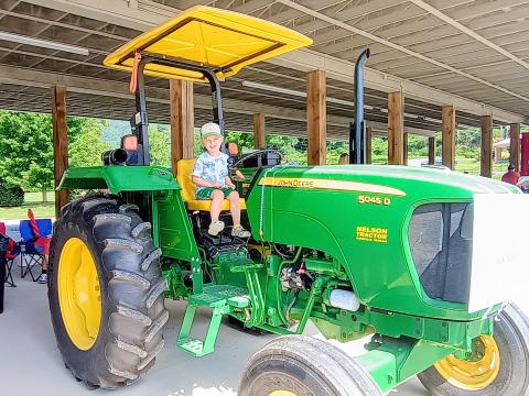 Megan Horn/The Clayton Tribune. Declan Alexander, 4, has fun playing on this farm tractor presented by Marty Franklin during the Aug. 16 “Touch-A-Truck” event. The family-friendly event allowed kids with their families to climb, “touch,” and explore many vehicles that represent our community heroes. 