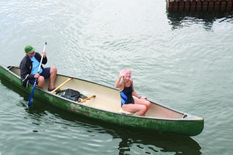 Wesley Branch/The Clayton Tribune. With her husband Steve paddling the boat, Cissy Jackson comes to the boat dock after swimming Lake Rabun in honor of her 60th birthday.